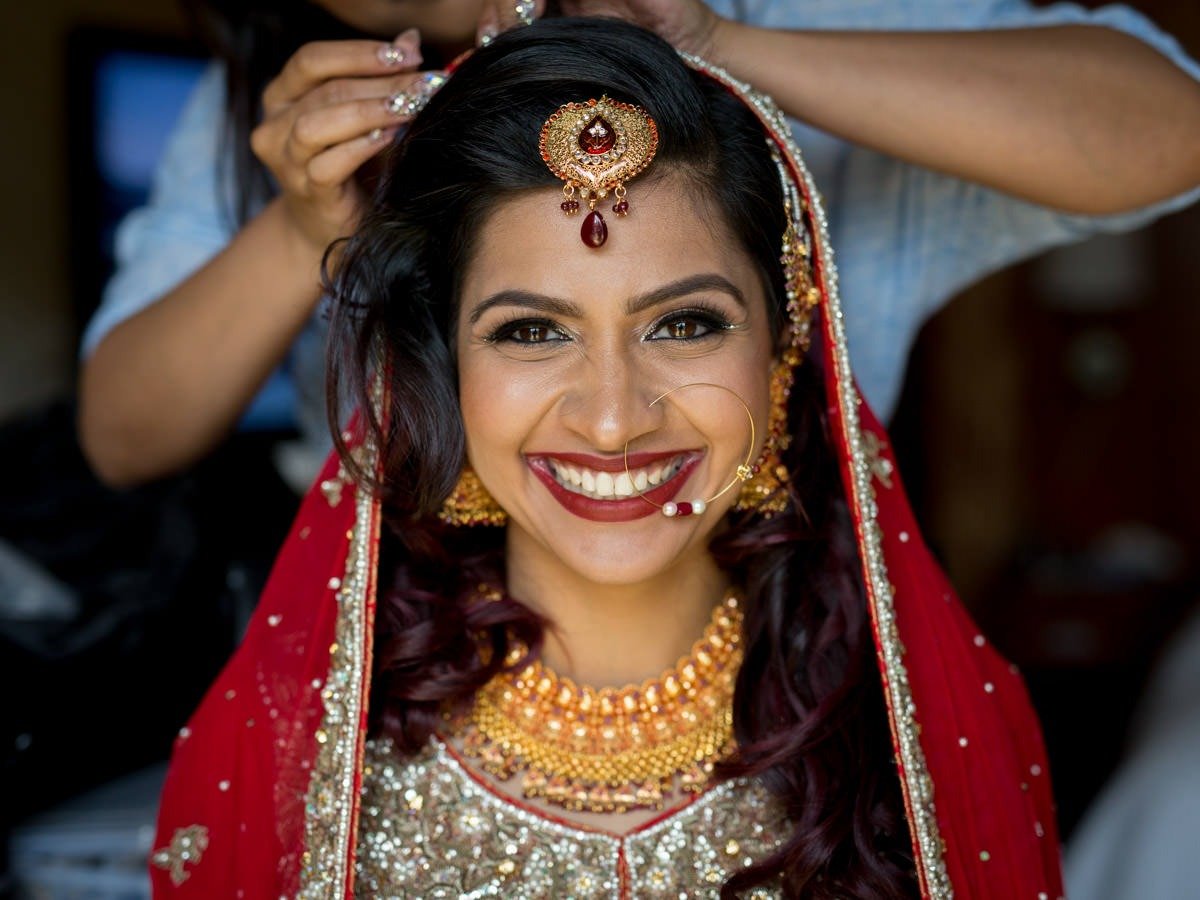 A Bengali bride smiles as she finishes getting ready for her wedding at Foxchase Manor in Manassas, Virginia.